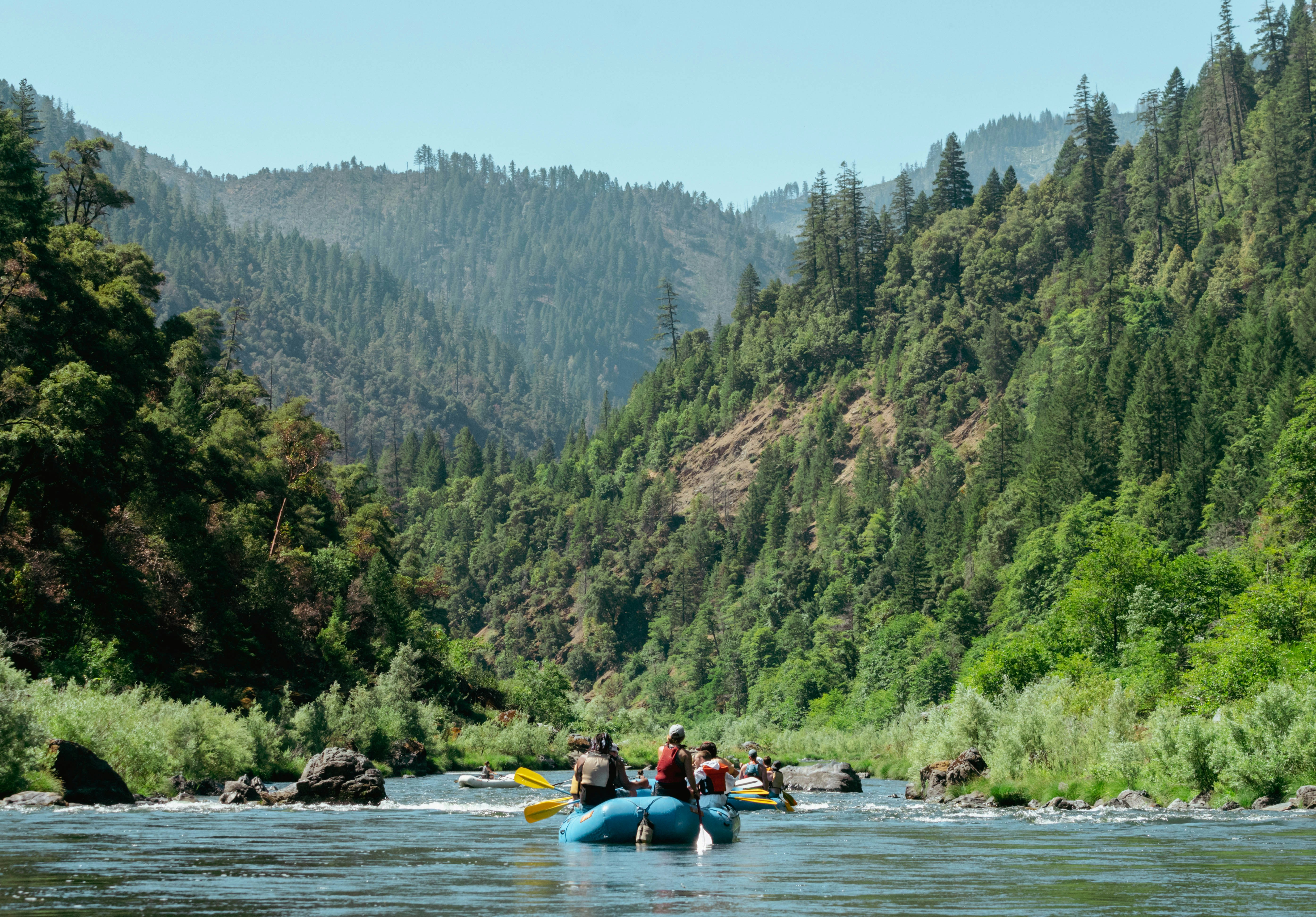 River Rafters surrounded by forrest hills.